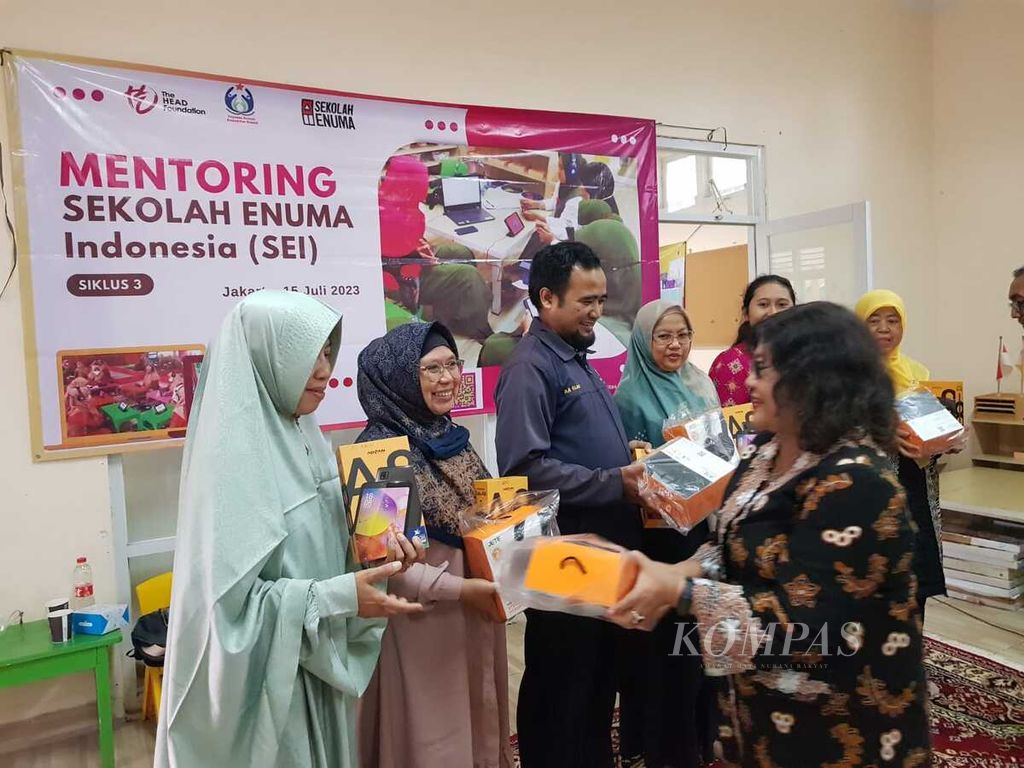 Ketua Yayasan Rumah Komunitas Kreatif (YRKK) Ella Yulaelawati (kanan) menyerahkan tablet pembelajaran kepada para guru peserta Mentoring Sekolah Enuma di TK Angkasa 1 Halim Perdanakusuma, Jakarta Timur, Sabtu (15/7/2023). 