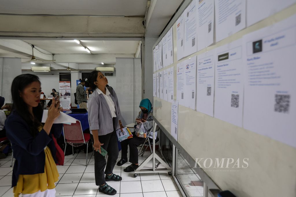 Seorang pencari kerja melihat sejumlah poster lowongan pekerjaan di acara <i>job fair</i> di Universitas Tama Jagakarsa, Jakarta Selatan, Selasa (25/4/2024).