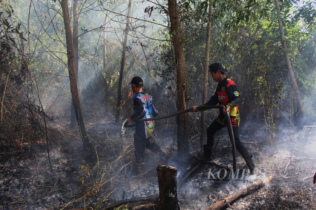 Dua petugas gabungan pemadam kebakaran mengejar 'kepala' api di tengah lahan yang terus membesar hingga mendekati pemukiman warga di Jalan Matal, Kota Palangkaraya, Kalteng, Minggu (13/8/2023). Api melahap lahan bergambut dengan total luas hampir 1 hektar.