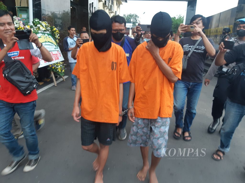 Dua tersangka yang masih berstatus pelajar berjalan dengan tangan terborgol di Polresta Cirebon, Kabupaten Cirebon, Jawa Barat, Jumat (6/1/2023). Keduanya menjadi tersangka kasus penganiayaan yang menewaskan seorang anak.