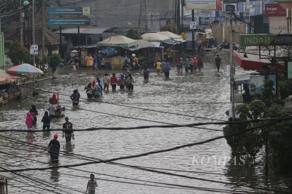 Buruh pabrik melintasi banjir di dayeuhkolot kabupaten bandung jawa barat