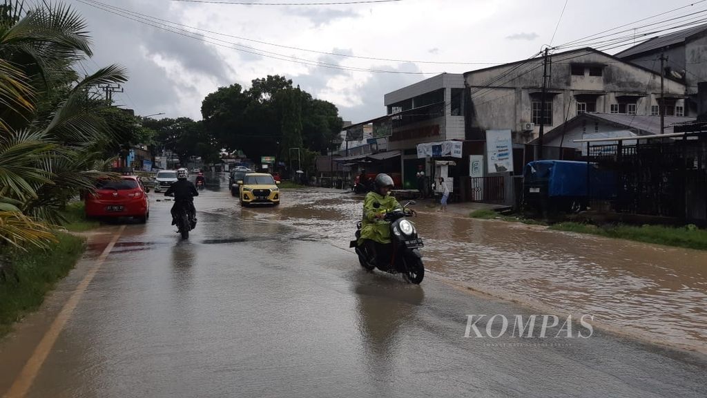 Warga melintasi jalan yang tergenang air meski hujan hanya beberapa waktu di Kendari, Sulawesi Tenggara, Selasa (12/3/2024). Banjir bandang menerjang wilayah ini pekan lalu yang membuat ribuan warga terdampak hingga satu orang meninggal.