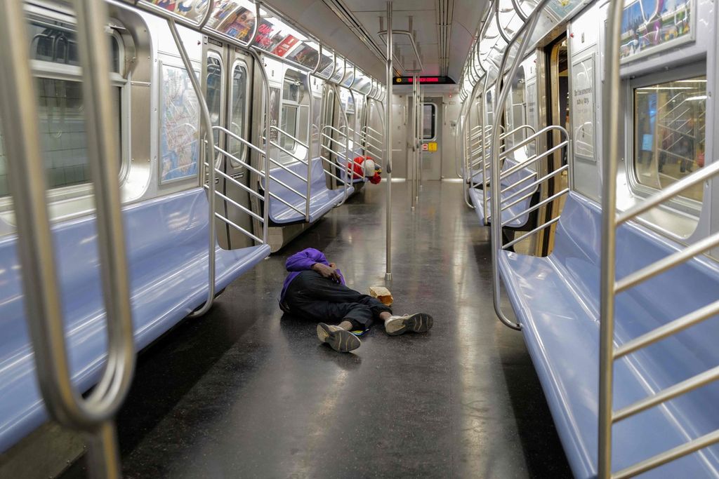 Dua tunawisma tampak tidur di gerbong MRT yang kosong, di Manhattan, New York City, Rabu (13/12/2023).