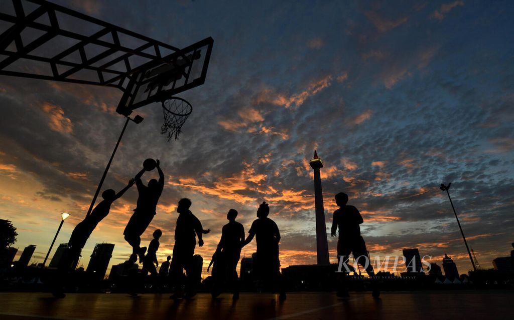 Warga bermain basket saat senja hari di lapangan basket di kawasan Monumen Nasional (Monas), Jakarta, Sabtu (29/12/2018). 
