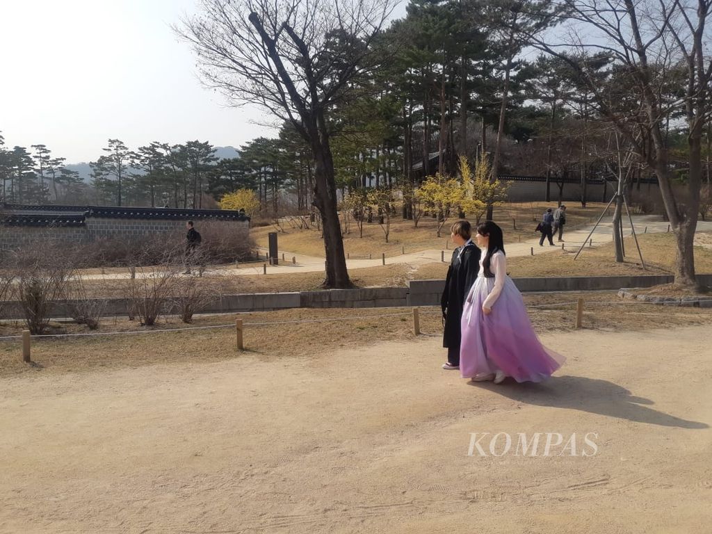 Pengunjung yang mengenakan hanbok berjalan-jalan di Istana Gyeongbokgung, Seoul, Korea Selatan, Maret 2023.