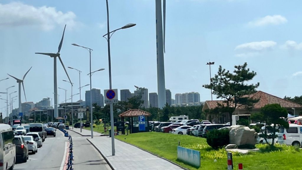 Kincir angin raksasa terpasang di tengah pemukiman warga di pinggir pantai di Kota Weihai, Provinsi Shandong, Sabtu (13/8/2022). (Kompas/Luki Aulia)