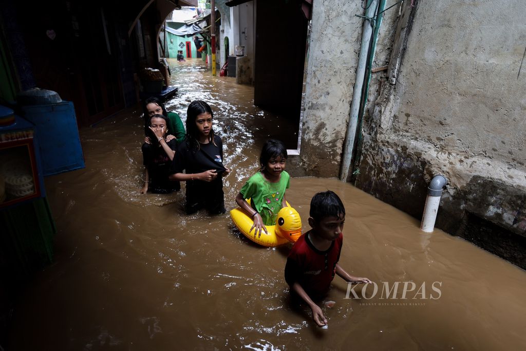 Anak dan remaja berjalan di salah satu gang yang tergenang banjir di Kelurahan Kampung Melayu, Kecamatan Jatinegara, Jakarta Timur, Kamis (30/11/2023). 