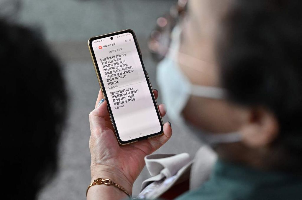 Seorang perempuan di Stasiun Seoul, Korea Selatan, Rabu (31/5/2023), membaca pesan berisi perintah evakuasi yang diterima melalui telepon selulernya, menyusul laporan peluncuran roket dan satelit Korea Utara. 