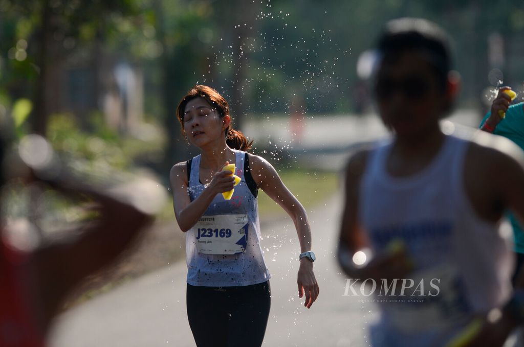 Perempuan pelari <i>half marathon </i>saat mendinginkan tubuhnya dengan spons saat mengikuti Borobudur Marathon 2023 Powered by Bank Jateng di kawasan Candi Borobudur, Kabupaten Magelang, Jawa Tengah, Minggu (19/11/2023). 