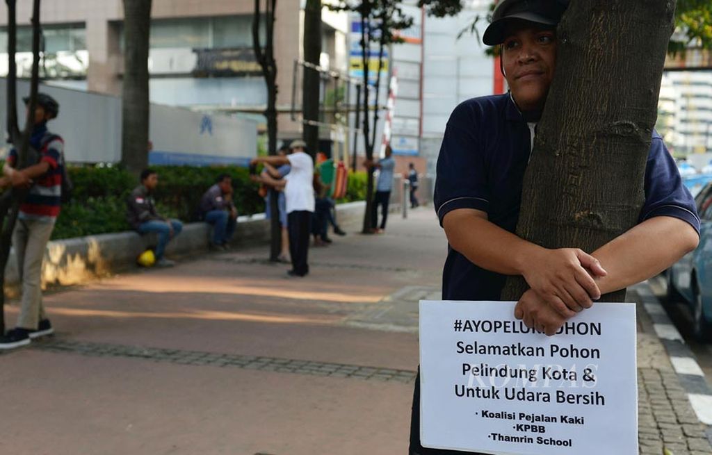 Koalisi Pejalan Kaki menggelar gerakan memeluk pohon di trotoar di Jalan Sudirman, Jakarta, Jumat (22/9). Gerakan itu bentuk  protes terhadap rencana Pemerintah Provinsi DKI Jakarta yang akan memangkas pohon sebagai dampak penataan jalan dan trotoar.