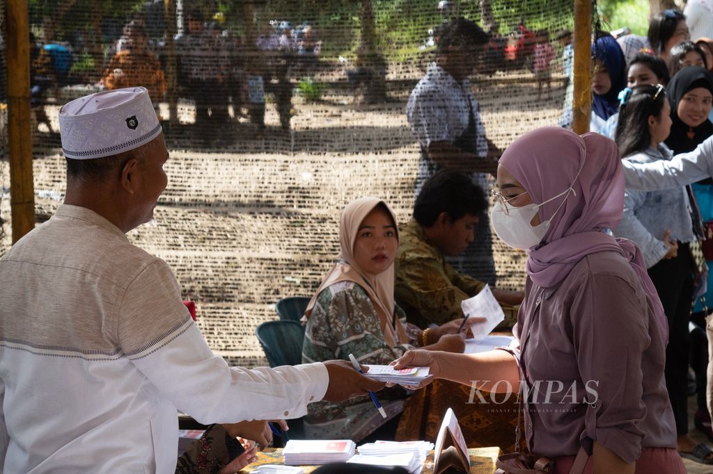 Petugas TPS memberikan surat suara kepada warga di Kampung Pasir Panjang, Pulau Rempang, Batam, Kepulauan Riau, Rabu (14/2/2024).