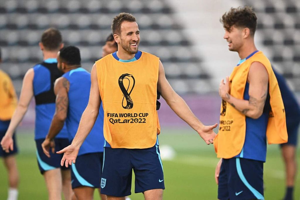 Kapten tim nasional Inggris Harry Kane (tengah) bebincang dengan bek John Stones di sela-sela latihan tim di Stadion Al Wakrah, selatan Doha, Qatar, Minggu (20/11/2022). 