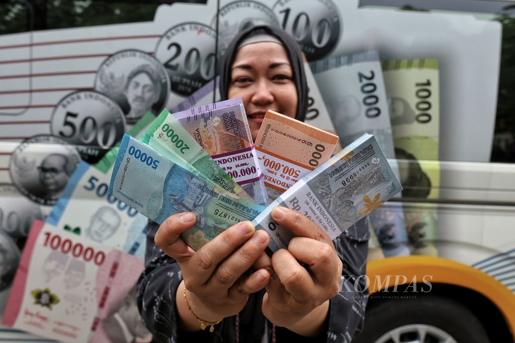 Warga memperlihatkan rupiah yang sudah ditukar di kas keliling Bank Indonesia di O2 Corner, Palmerah Selatan, Jakarta, Selasa (26/3/2024). 