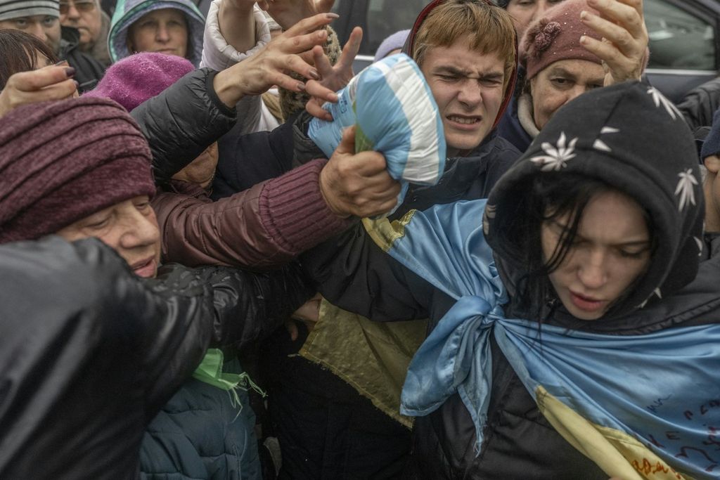 Warga Kherson, Ukraina, berebut bantuan yang dibagikan pada Kamis (17/11/2022).  Kala suhu minus 2 derajat celsius pada Kamis, warga kota itu mengantre pembagian bantuan kemanusiaan dari sejumlah lembaga amal.