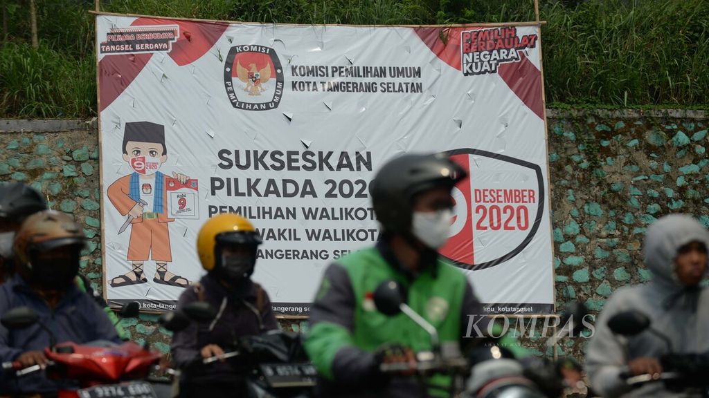 Warga melintasi baliho sosialisasi pelaksanaan Pemilihan Kepala Daerah (Pilkada) Kota Tangerang Selatan di Jalan Ciater, Serpong, Tangerang Selatan, Banten, Jumat (11/9/2020). 