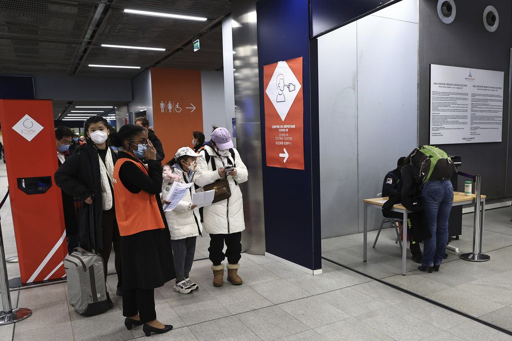 Penumpang yang datang dari China menunggu di depan area tes Covid-19 di Bandara Charles de Gaulle di Roissy, luar Paris, Perancis, Minggu (1/1/2023). Perancis mewajibkan hasil tes negatif untuk semua penumpang yang datang dari China. 