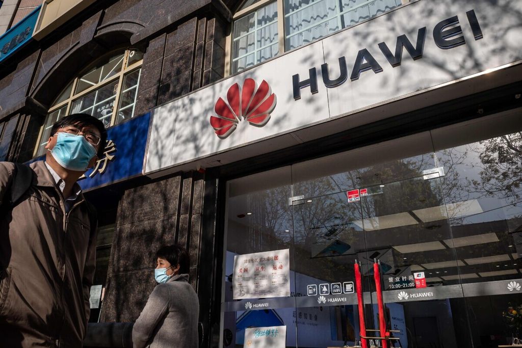 Dalam foto yang diambil pada 22 April 2020, warga berjalan melewati toko Huawei di Beijing, China.
