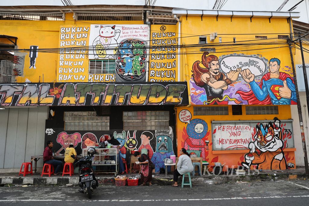 Warga beraktivitas di depan mural bertema ”Ayo Rukun”, di Jalan Pajajaran, Kota Magelang, Jawa Tengah, Senin (23/5/2022). Mural tersebut diselesaikan oleh 28 perupa jalanan sehari sebelumnya. Melalui mural itu masyarakat diajak untuk semakin meningkatkan kerukunan saat kondisi pandemi dinilai telah membaik.