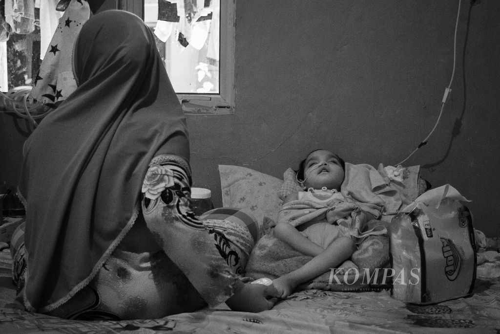 Eva Nurmala merawat anaknya, Nasifa, yang mengalami kelumpuhan di rumah mereka di Batam, Kepulauan Riau, 17 Juni 2023. Anak itu menjalani perawatan di rumah setelah dinyatakan pulih dari gangguan ginjal akut progresif atipikal.