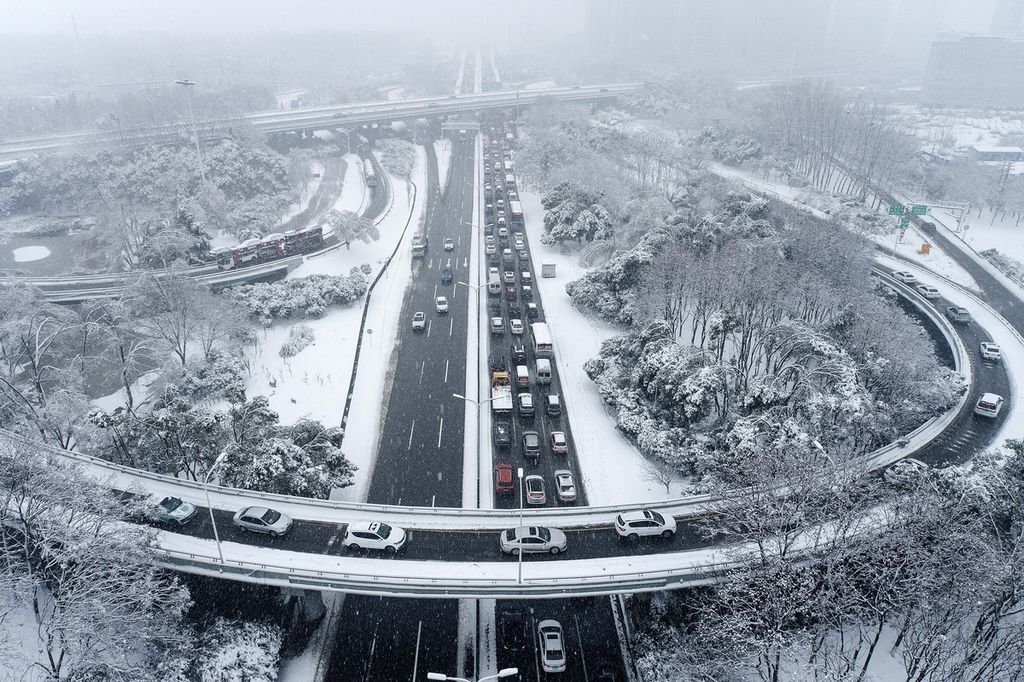 Kendaraan berjalan di tengah kondisi lalu lintas yang padat saat hujan salju di Wuhan, di Provinsi Hubei, China, Selasa (6/2/2024). Perjalanan jutaan warga China menuju kampung halaman jelang Imlek kacau akibat badai salju.