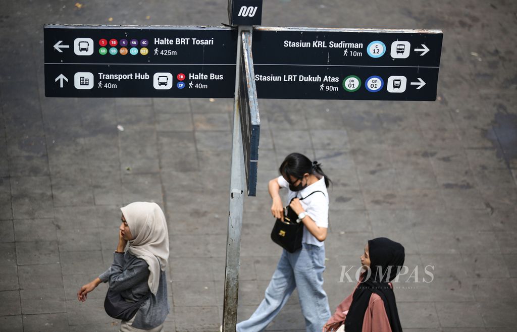 Penumpang kereta komuter melintas di papan penunjuk arah tak jauh dari stasiun Sudirman, Jakarta Pusat, Selasa (10/9/2024). 