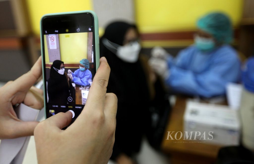 Tenaga kesehatan memotret rekannya yang menerima suntikan vaksinasi penguat di sentra vaksin Gelanggang Remaja Pulogadung, Jakarta, Selasa (1/8/2022). 