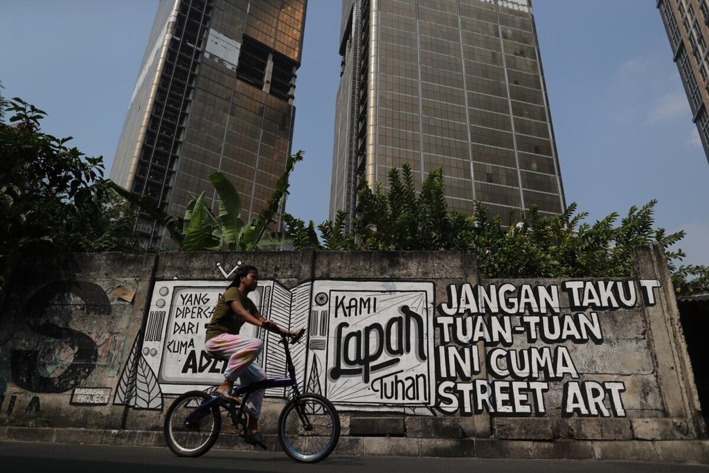 Warga melintas di depan mural kritik sosial di kawasan Tanah Abang, Jakarta, Rabu (25/8/2021). Mural tersebut merupakan wujud ekspresi para seniman jalanan dalam melihat fenomena keresahan yang terjadi di tengah masyarakat saat ini.