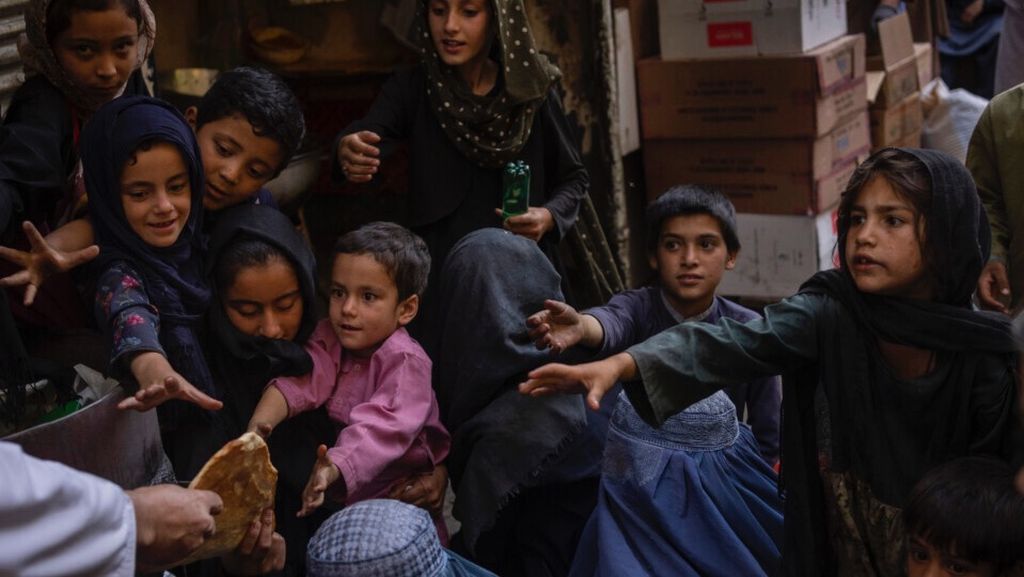 Sejumlah anak dan orangtuanya berebut roti yang diberikan donor untuk dibawa ke rumah masing-masing di Kabul, Afghanistan, Kamis (16/9/2021).