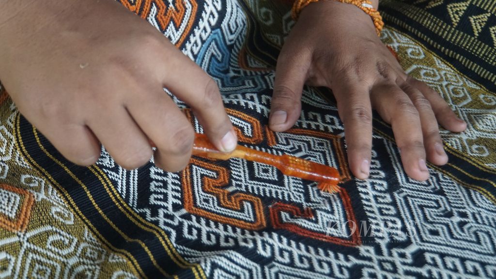 Pemudi adat Sumba, Kristine Hara Tola, mewarnai pola pada kain-kain tenun Sumba di teras rumahnya di Kampung Patanning, Desa Rindi, Sumba Timur, Selasa (9/1/2024).