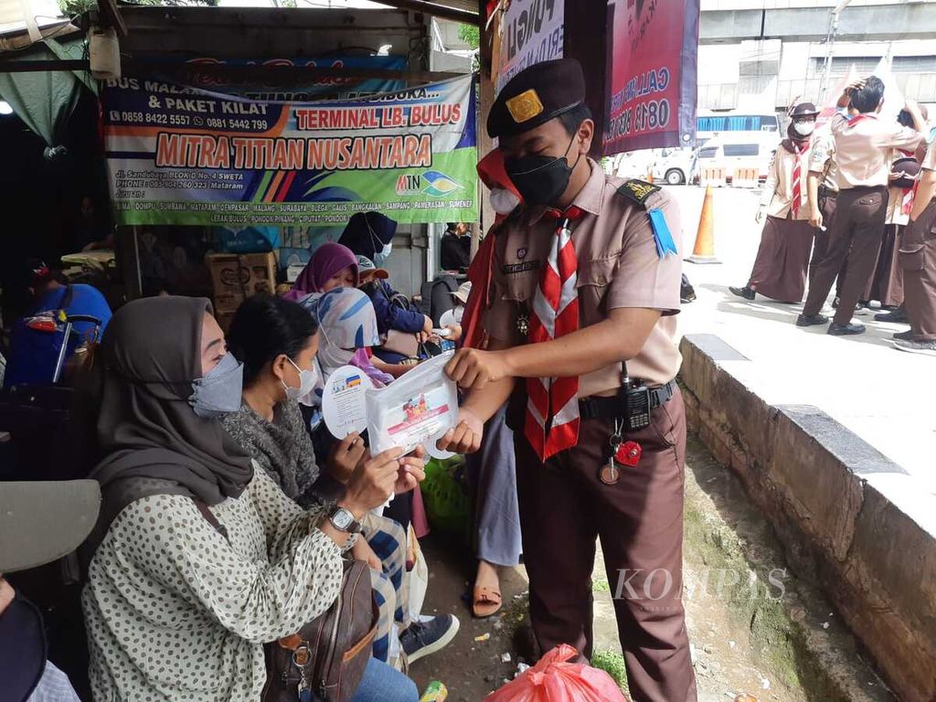 Bintang Kusuma, anggota Pramuka yang bertugas di Terminal Lebak Bulus, membagikan kit berisi masker dan kipas kepada pemudik di Jakarta, Jumat (29/4/2022).