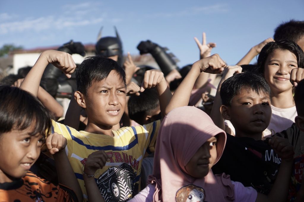 Anak-anak berpose saat berfoto bersama sosok yang dikenal sebagai Om Batman di tengah puing rumah yang terbakar di Kelurahan Baru Ulu, Kecamatan Balikpapan Barat, Kota Balikpapan, Kalimantan Timur, Selasa (8/6/2021) sore.