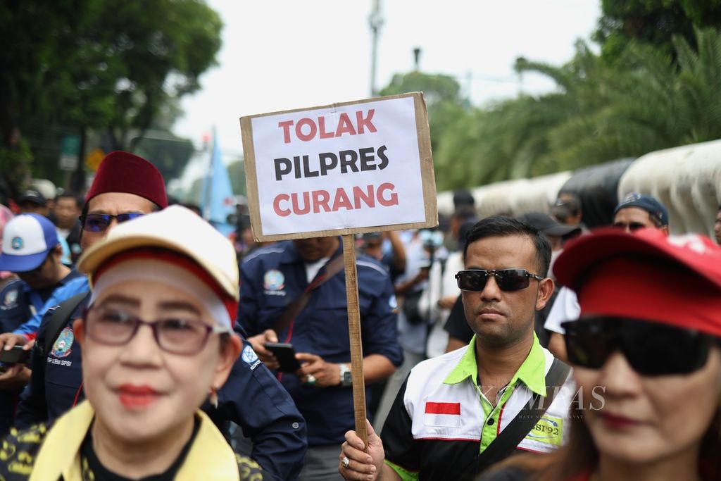 Seorang peserta aksi membawa poster berisi tuntutan mereka di depan Kantor Komisi Pemilihan Umum (KPU), Jakarta, Rabu (21/2/2024). Peserta aksi yang tergabung dalam Poros Buruh menilai terdapat banyak permasalahan dalam pelaksanaan pemilu tahun ini. 