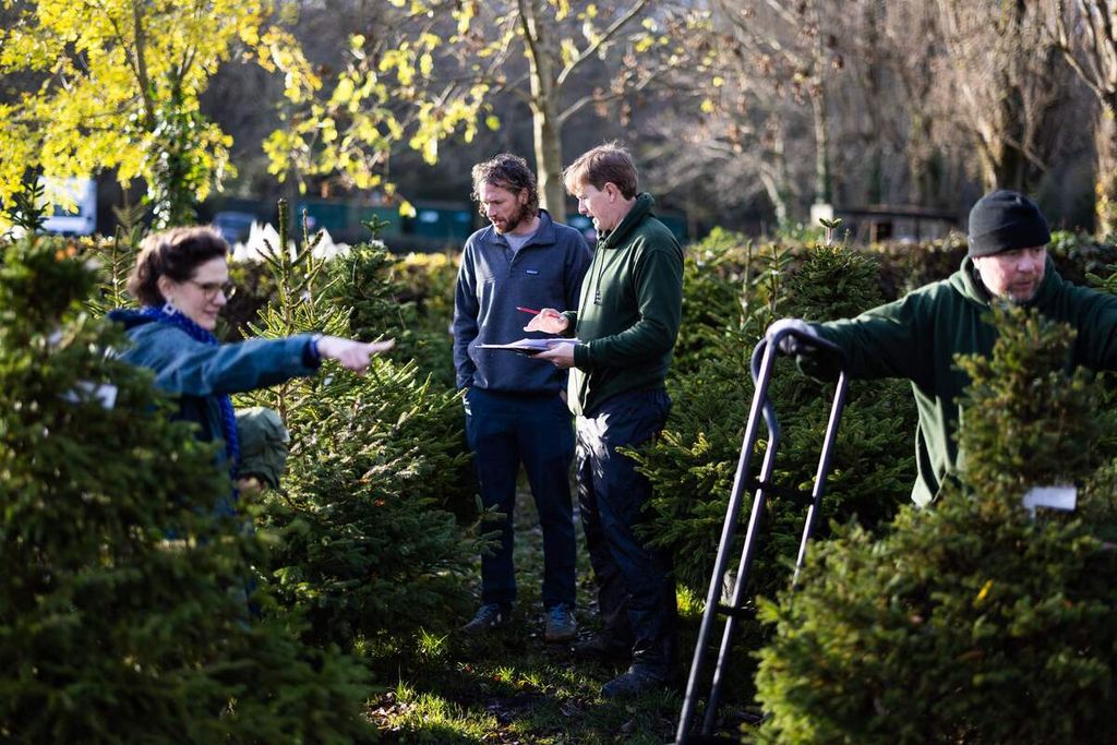 Jonathan Mearns, Direktur London Christmas Tree Rental (tengah), dan koleganya, Nicholas (kanan), membantu pelanggan mengambil pohon cemara yang ia sewa tahun lalu dan tahun ini ia sewa lagi di tempat penyewaan pohon di Dulwich, London, Inggris, Jumat (8/12/2023). 