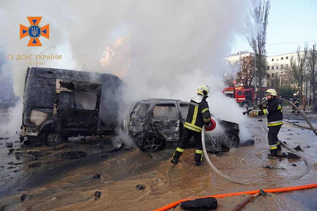 Petugas mencoba memadamkan api yang menghanguskan dua kendaraan di Kyiv, Ukraina, Senin (10/10/2022), akibat serangan roket Rusia ke Ukraina. 
