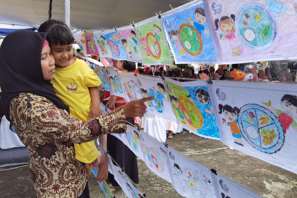 Seorang ibu mengajak putrinya melihat karya peserta lomba mewarnai Isi Piringku dalam rangkaian program Aksi Gizi Generasi Maju yang diselenggarakan Danone Indonesia di Pasar Seni Banyumulek, Kabupaten Lombok Barat, Nusa Tenggara Barat, Kamis (9/2/2023). Sejak 2018 hingga 2022, Program Isi Piringku PAUD telah menjangkau 6.732 PAUD, 15.436 guru, 175.085 siswa, dan 164.774 orangtua di 27 kabupaten kota di 9 provinsi di Indonesia. Program tersebut dalam rangka mendorong peningkatan gizi seimbang untuk mencegah tengkes atau <i>stunting</i>.