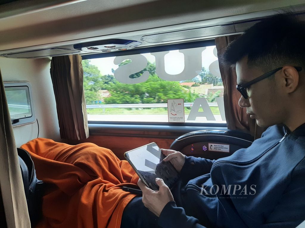 Penumpang &quot;sleeper bus&quot;, Badi Bastian (28) sedang bermain gawai untuk mengisi waktu luang dalam perjalanannya dari Ciputat, Tangerang Selatan menuju Semarang, Jawa Tengah pada Senin (1/4/2024). 
