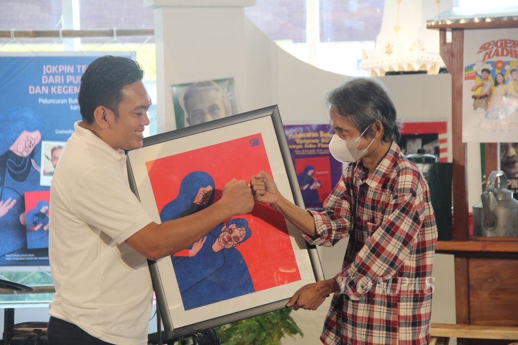 General Manager Gramedia Pustaka Utama Andi Tarigan (kiri) menyerahkan gambar sampul buku kumpulan puisi <i>Epigram 60</i> kepada penyair Joko Pinurbo, Senin (16/5/2022), di Toko Buku Gramedia Sudirman, Yogyakarta. <i>Epigram 60 </i>merupakan kumpulan puisi terbaru Joko Pinurbo yang diterbitkan untuk merayakan ulang tahun sang penyair ke-60.