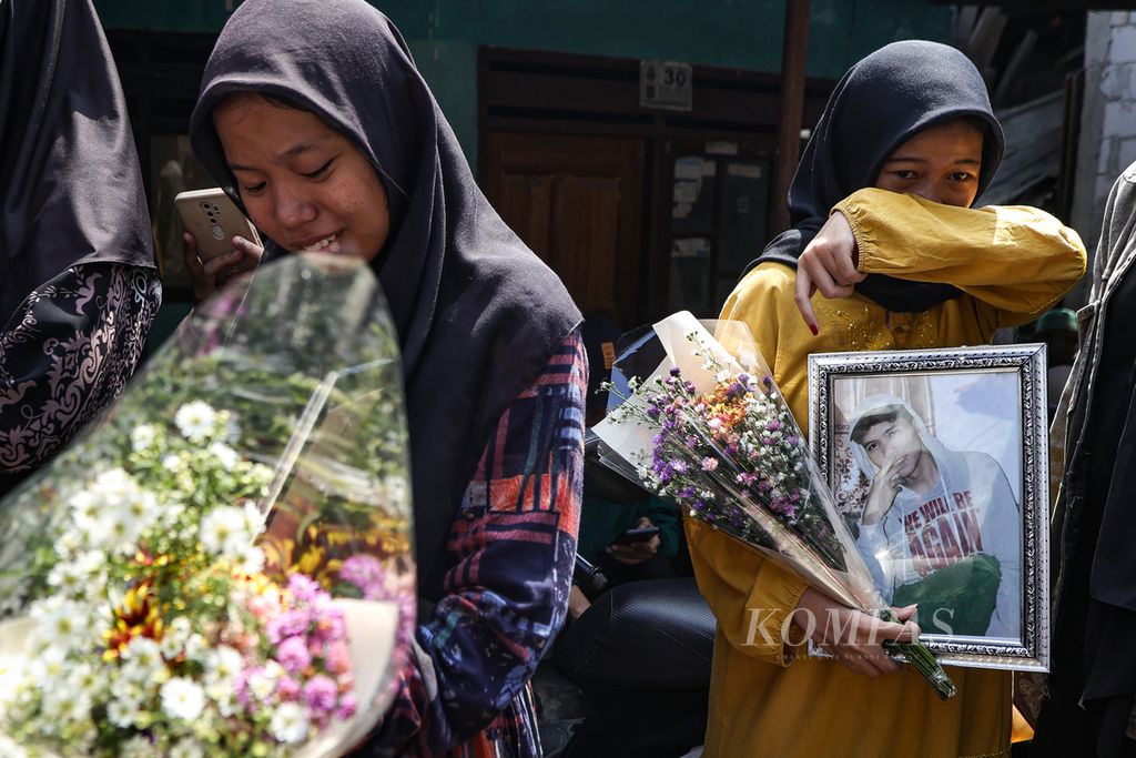 Kerabat menangis sembari membawa foto korban kecelakaan bus di Subang, Mahesya Putra, di sekitar rumah duka di Depok, Jawa Barat, Minggu (12/5/2024). 