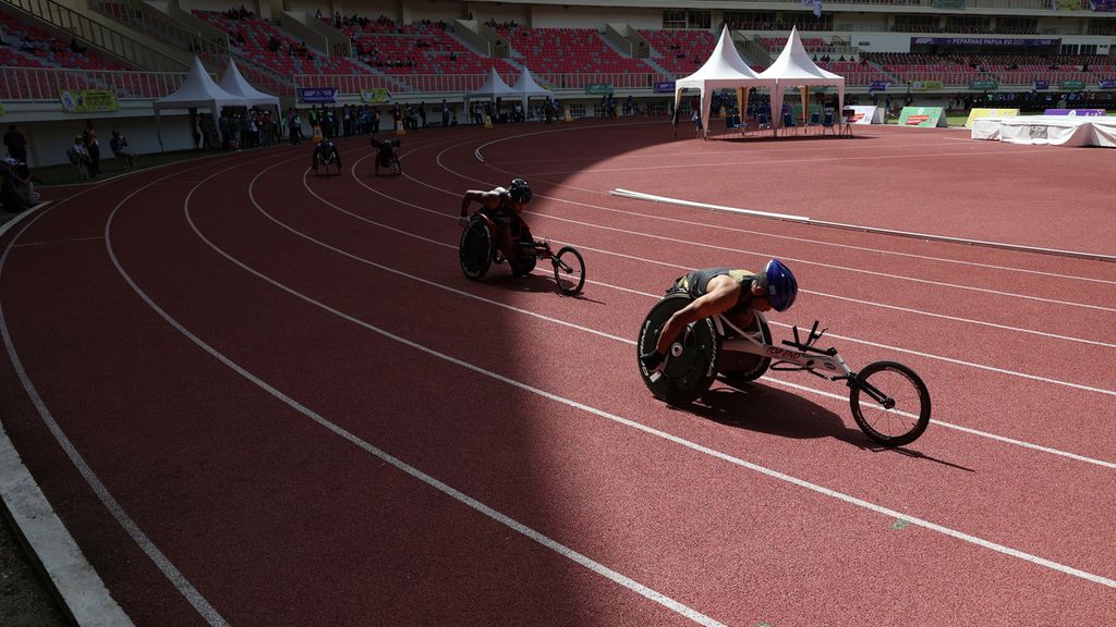 Atlet kursi roda DKI Jakarta, Moh Agung (kanan), melaju pada babak penyisihan balap kursi roda klasifikasi T54 Peparnas Papua 2021 di Stadion Lukas Enembe, Kabupaten Jayapura, Papua, Sabtu (6/11/2021).