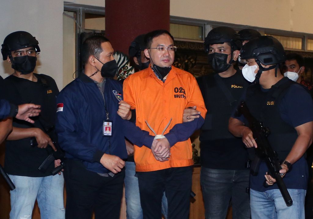Petugas kepolisian memperlihatkan tersangka bandar besar judi <i>online</i> Apin Bak Kim alias Apin BK saat tiba di Bandara Soekarno-Hatta, Tangerang, Banten, Jumat (14/10/2022) malam. Polisi menangkap Apin BK di Malaysia setelah dua bulan melarikan diri dari Sumatera Utara.