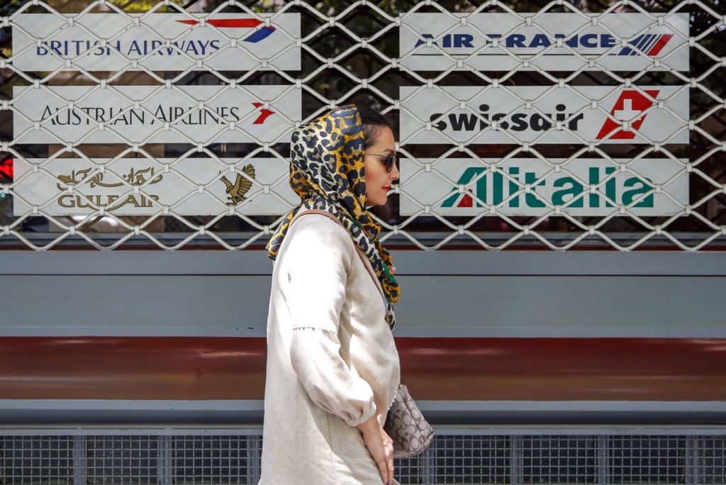 Seorang perempuan warga Iran berjalan melewati sebuah gerai agen perjalanan di Teheran, Iran, 24 Agustus 2018. 