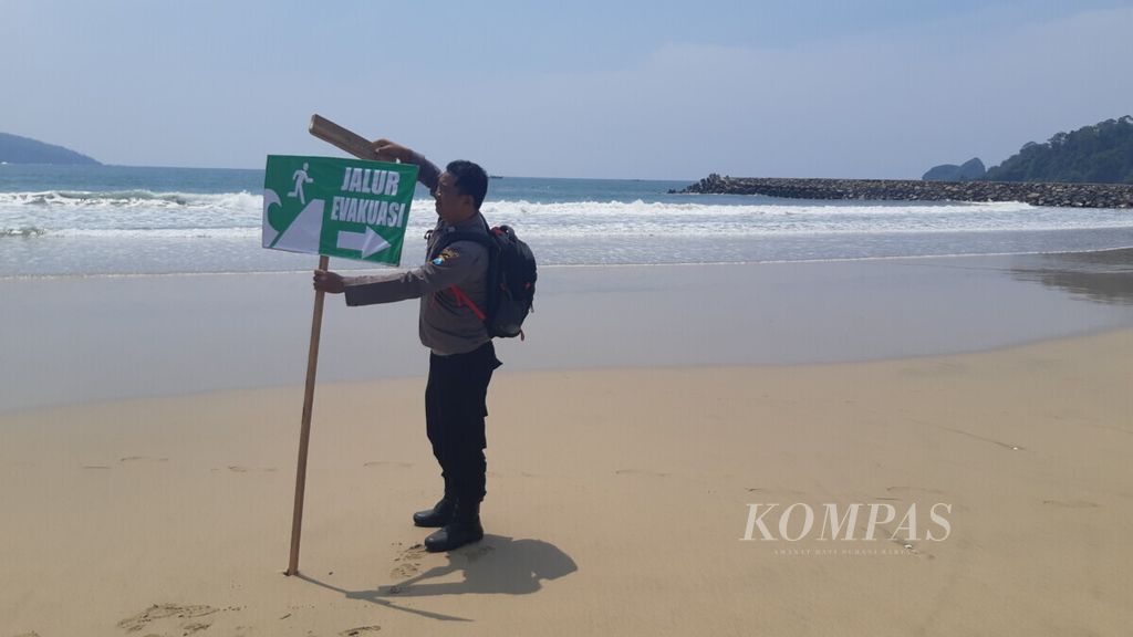 Petugas memasang rambu-rambu jalur evakuasi. Adegan tersebut ditampilkan dalam simulasi penanganan bencana tsunami di Pantai Mustika, Desa Pancer, Banyuwangi, Jawa Timur, Sabtu (5/1/2019).