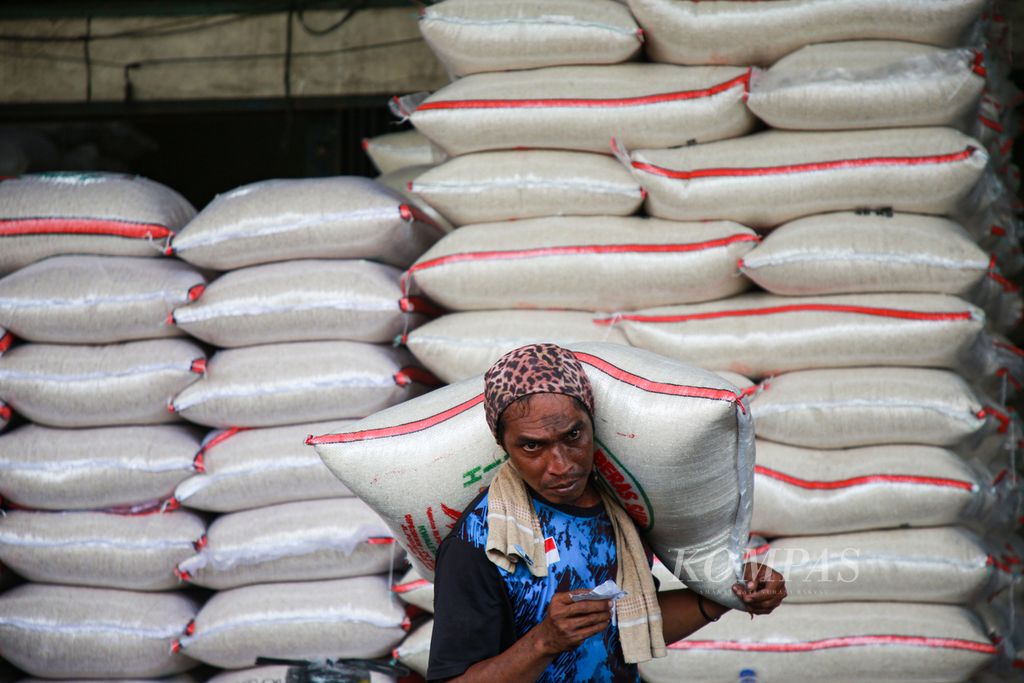 Buruh pikul bersiap memuat beras ke kendaraan pembeli di pasar induk beras Cipinang, Jakarta Timur, Kamis (15/12/2022).