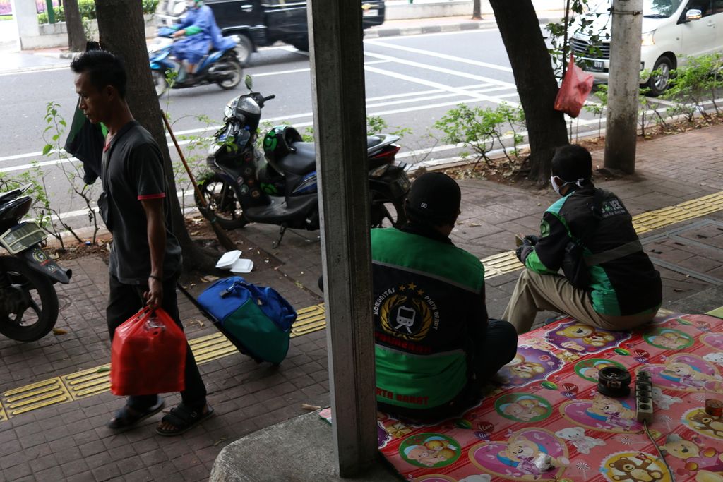 Dua pengemudi ojek daring menunggu penumpang di tepi Jalan Tentara Pelajar, Kelurahan Gelora, Kecamatan Tanah Abang, Jakarta Pusat, Senin (3/10/2022).