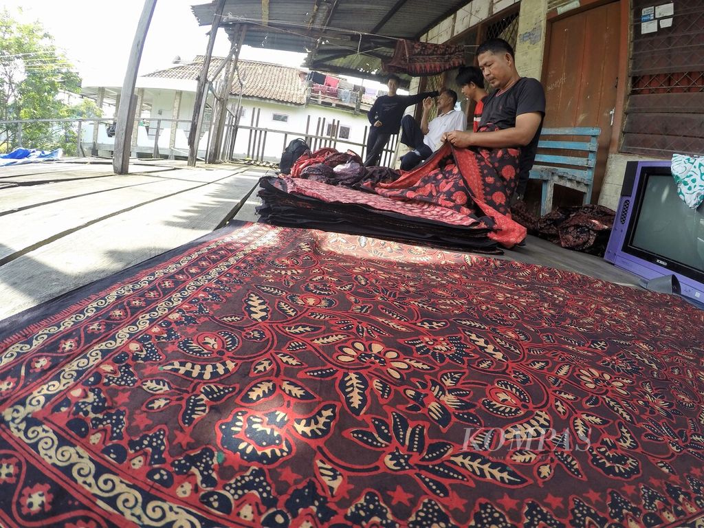 Perajin melipat kain batik seusai dijemur di usaha Rumah Batik Azmiah, kawasan Seberang Kota Jambi, Selasa (10/1/2023). Usaha batik yang semua tumbuh di kawasan Seberang Kota Jambi kini meluas ke sejumlah daerah sekitar.