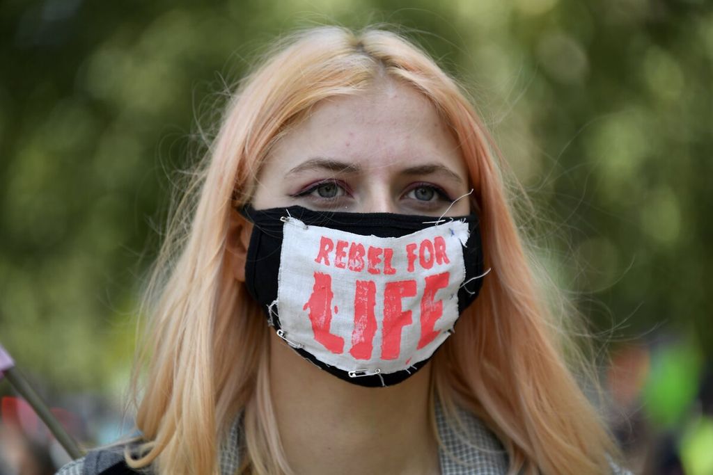 Salah seorang peserta mengenakan masker dalam aksi memprotes kebijakan penanganan perubahan iklim di luar Istana Buckingham, London, Inggris, Selasa (1/9/2020).