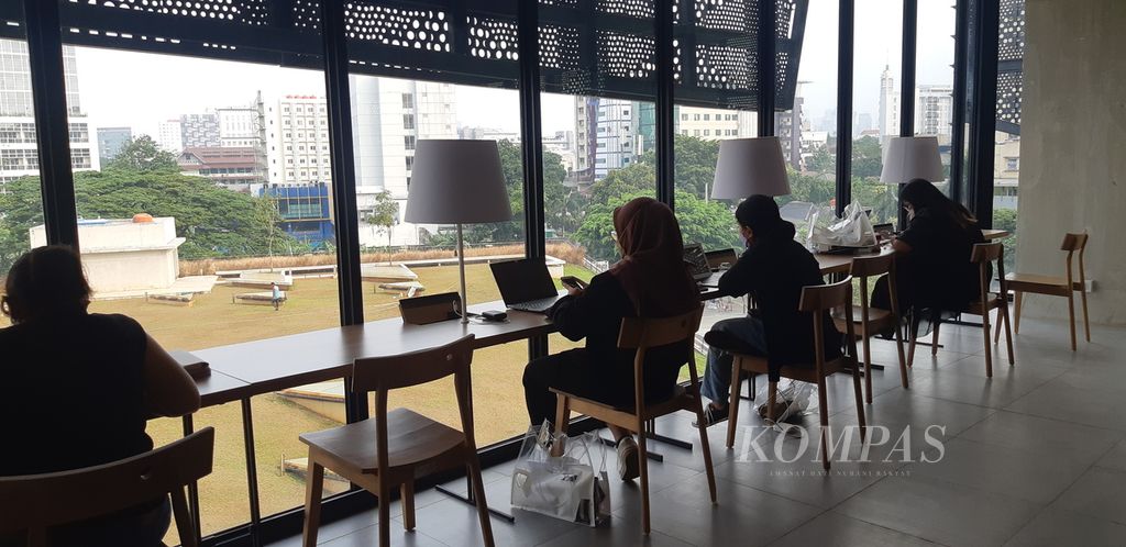 Beberapa pengunjung Perpustakaan Jakarta, Cikini, Jakarta Pusat tengah beraktivitas di meja kerja di satu sisi perpustakaan.
