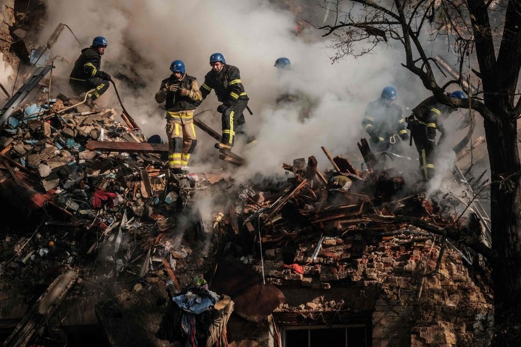 Petugas pemadam kebakaran tengah mencoba mencari korban setelah sebuah gedung rusak akibat serangan drone, yang diduga diproduksi Iran di Ibu Kota Ukraina, Kyiv, Senin (17/10/2022).  (Photo by Yasuyoshi CHIBA / AFP)