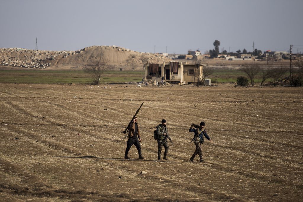 Tiga anggota Pasukan Demokratik Suriah dukungan Amerika Serikat melintas sebuah lahan pertanian di kota Hassakeh, Suriah, Jumat (28/1/2022). Pemerintah Suriah dan Irak kini mewaspadai kebangkitan kelompok NIIS di negara tersebut.