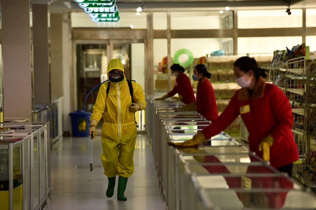 Foto yang diambil pada 18 Maret 2022 memperlihatkan seorang petugas kesehatan tengah menyemprotkan cairan disinfektan ke lantai sebuah supermarket di Pyongyang, Korea Utara. Pemerintah Korut, Kamis (12/5/2022) secara resmi mengumumkan adanya kasus Covid-19 pertama di negara itu. 